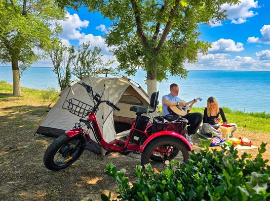 Recreational fat tire electric tricycle suited for outdoor leisure, demonstrating capability on lakeside grass next to a couple camping